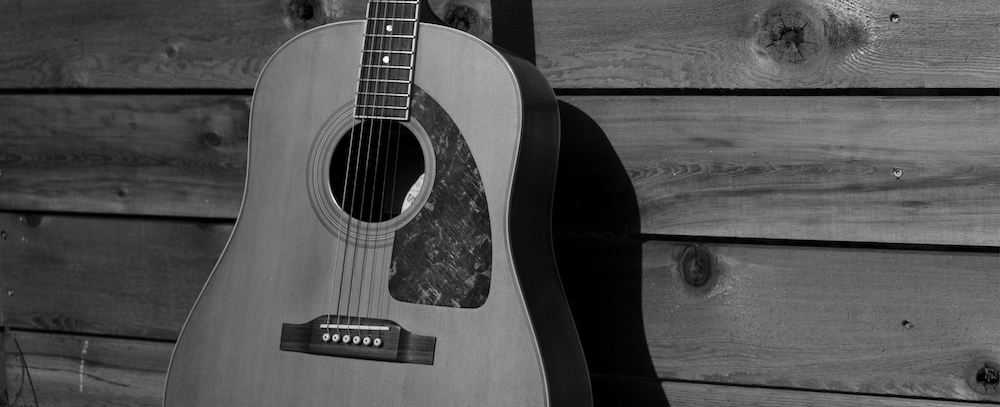 Acoustic guitar against fence